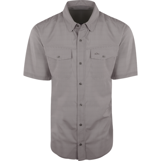 A close-up of the Traveler's Check Shirt S/S, a lightweight and breathable shirt with four-way stretch for freedom of movement. Features moisture-wicking fabric and two chest pockets with button flaps. Ideal for the man on the go.