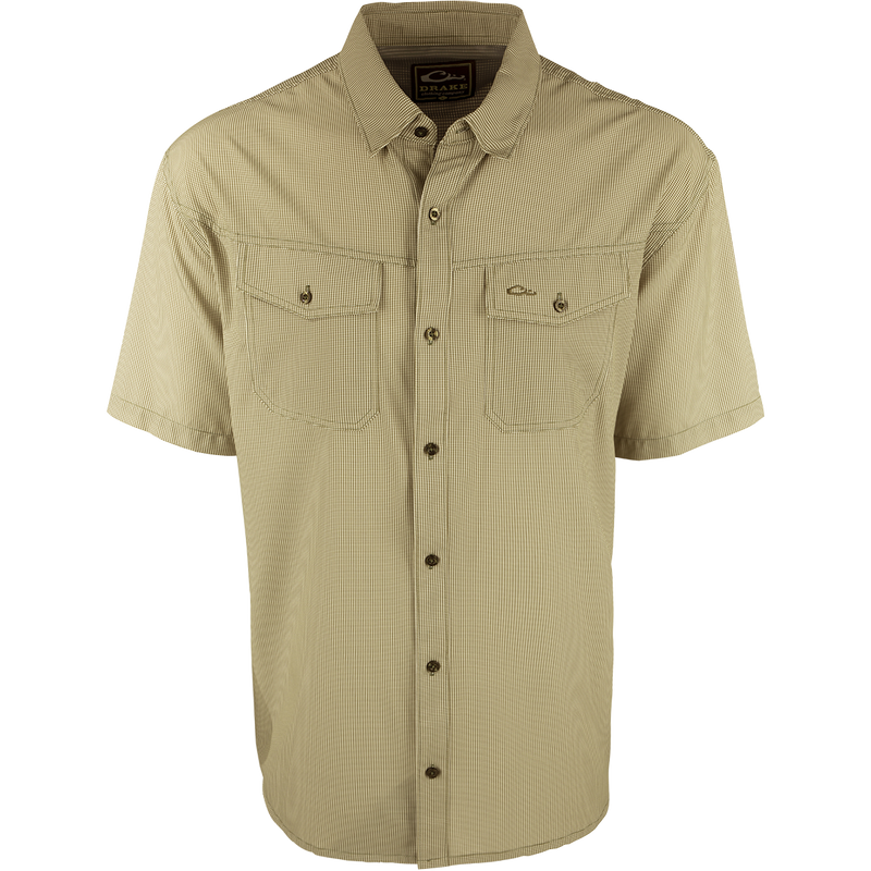 A close-up of the Traveler's Check Shirt S/S, a lightweight and breathable poly/spandex shirt with four-way stretch for freedom of movement. Ideal for the man on the go, it features moisture-wicking technology and 2 chest pockets with button flaps. Perfect for exotic vacations or running around town.