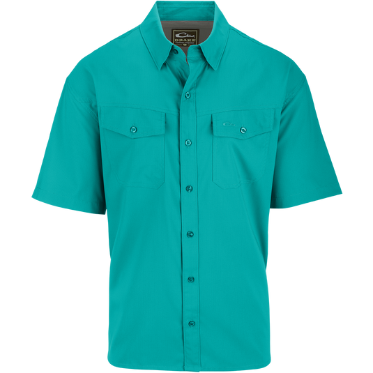 A close-up of the Traveler's Solid Dobby Shirt S/S, featuring a hidden button-down collar, two chest pockets with button-through flaps, and a split tail hem. Constructed with 100% Polyester textured dobby fabric, this shirt is featherweight at 79 GSM, moisture-wicking, and quick-drying. It also offers UPF30 sun protection. Versatile for any occasion, this shirt is perfect for seasons to come.